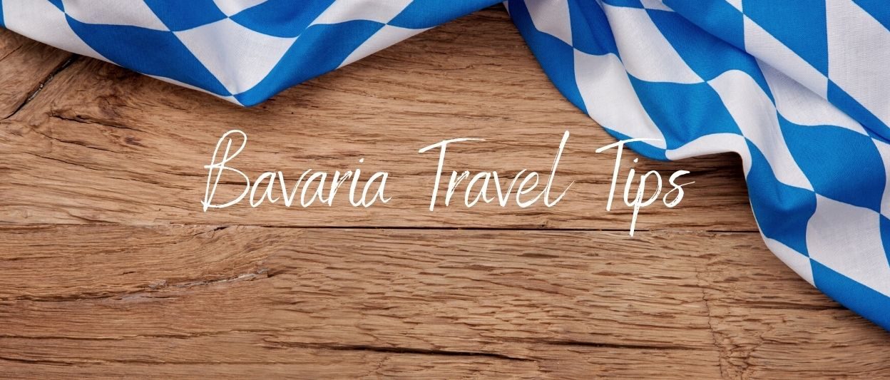 Blue white bavarian flag on a wood table. white text overlay: Bavarian Travel Tips