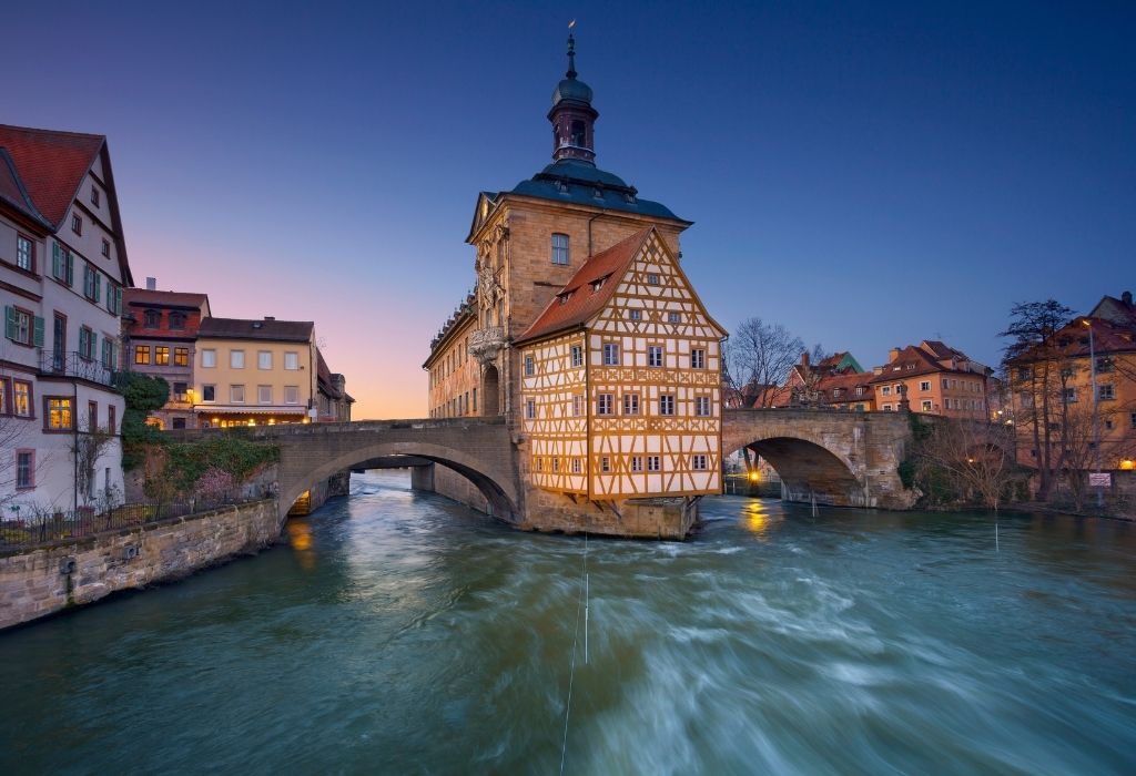 two arched bridges over a river with a yellow/white half-timbered house in the middle of the bridge - City Hall Bamberg